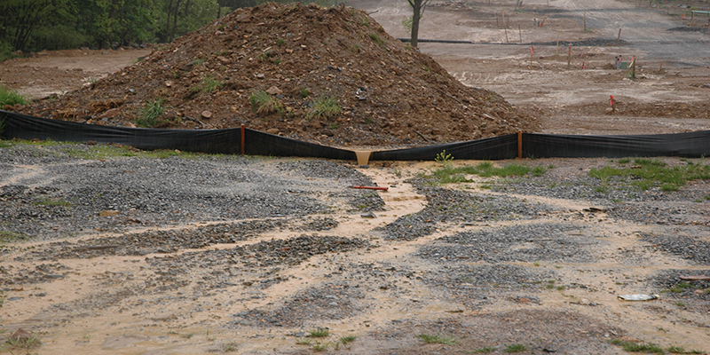 Muddy water flowing over silt fence